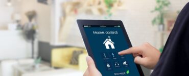 uomo che digita qualcosa su tablet collegato ad una casa