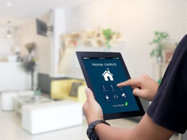 uomo che digita qualcosa su tablet collegato ad una casa